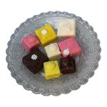 8 Artificial French fancy cakes, small and medium in sizes, displayed on clear glass dish in colours, brown , pink ,yellow, cream